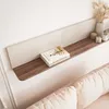 A shelf mounted on a wall above a sofa, with books and decorative items on it. Náhled obrázku produktu