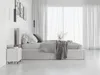 A modern bedroom with a white upholstered bed, grey bedding, and sheer white curtains. Produktbild-Vorschau