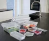 A collection of plastic food storage containers with green lids on a kitchen counter. Voir les images du produit