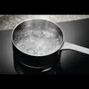 A pot of boiling water on a black induction hob. Voir les images du produit