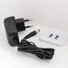 A black power adapter with a European plug and a white dual USB adapter are placed on a white surface. Produktbild-Vorschau