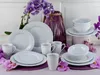 A white porcelain dinnerware set is arranged on a table with purple orchids and a purple vase in the background. Náhľad obrázku produktu