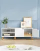 A white media console with wood legs against a light blue wall. Náhled obrázku produktu
