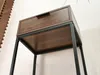 A close-up view of a narrow console table with a wooden drawer and black metal legs. Náhled obrázku produktu