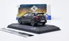 A black model car is displayed on a black stand, with its packaging in the background. Produktbild-Vorschau