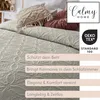 A close-up view of a quilted bedspread with decorative pillows and text overlays. Produktbild-Vorschau