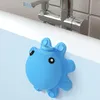 A blue octopus-shaped bathtub overflow drain cover is attached to the side of a bathtub, with a faucet visible in the background. Produktbild-Vorschau