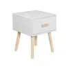 A white nightstand with a single drawer and wooden legs, shown against a white background. Podgląd zdjęcia produktu