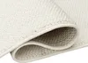 A close-up view of a rolled-up cream-colored rug, showing the texture of the material and the bound edge. Anteprima dell’immagine prodotto