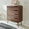 A wooden dresser with four drawers stands against a black and white grid-patterned wall. Produktbild-Vorschau