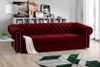 A red sofa in a living room setting with a bookshelf in the background and a rug in the foreground. Produktbild-Vorschau