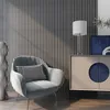 A modern living room scene featuring a gray armchair with a black and white patterned cushion, a tall decorative vase, and a cabinet with a lamp and artwork. Produktbild-Vorschau