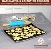 A baking sheet with cookie dough cutouts and a rolling pin on a kitchen counter. Produktbild-Vorschau