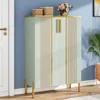 A light green shoe cabinet with gold accents stands against a blue wall, next to a white door. Produktbild-Vorschau