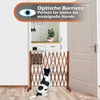 A wooden dog gate is set up in a doorway, with a black and white dog sitting in front of it, looking up. Produktbild-Vorschau