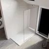 A modern bathroom with a walk-in shower and a washing machine visible. Voir les images du produit