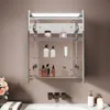 A bathroom cabinet with shelves displaying various toiletries and decorative items, mounted above a sink area with faucets. Náhled obrázku produktu