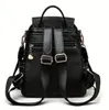 The back view of a black leather backpack with adjustable straps and a small charm. Podgląd zdjęcia produktu