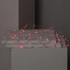 A string of red LED lights is draped over two light gray surfaces. Produktbild-Vorschau