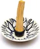 A palo santo stick is placed in a decorative ceramic holder. Voir les images du produit