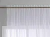A white sheer curtain hanging on a rod above a window. Produktbild-Vorschau