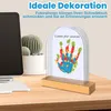 A decorative handprint frame on a desk next to a computer and a cactus. Produktbild-Vorschau