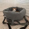 A cat sits in a gray pet carrier on a wooden floor, with a white brick wall in the background. Produktbild-Vorschau