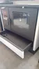 A close-up view of a wood-burning stove with a glass door and an open drawer. Produktbild-Vorschau