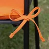 A close-up of an orange cushion tie on a black chair leg. Produktbild-Vorschau