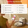 A person is holding a smartphone displaying an app interface, with a robot vacuum cleaner and its charging station in the background. Produktbild-Vorschau