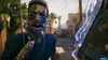 A first-person perspective of a zombie in a street setting, holding a weapon that is crackling with electricity. Produktbild-Vorschau