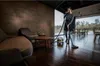 A woman is vacuuming a modern living room with large windows. Náhled obrázku produktu