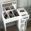A white vanity table with its mirror open, displaying various makeup products and accessories organized within its compartments. A Newton's cradle toy is visible on the tabletop. Produktbild-Vorschau
