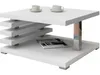 A white coffee table with a modern design, featuring two shelves and a chrome leg. Two coffee cups and saucers are on the top shelf, and a magazine is on the lower shelf. Náhľad obrázku produktu