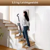 A woman is walking up a wooden staircase while holding a cordless vacuum cleaner. Produktbild-Vorschau