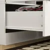 A close-up view of an open drawer in a white wardrobe, showing a folded plaid blanket inside. Produktbild-Vorschau