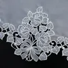 A close-up of white lace embroidery with rose and leaf motifs on a black background. Produktbild-Vorschau