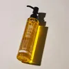 A bottle of cleansing oil with a pump dispenser, casting a shadow on a plain background. Produktbild-Vorschau