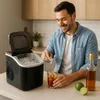 A man is making a drink with ice from an ice maker in a kitchen setting. Náhled obrázku produktu