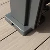 A close-up view of the base of a gray pergola post resting on a light-colored wooden deck. Produktbild-Vorschau