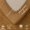 A close-up view of a fitted sheet corner, showing its texture and elastic edge, laid on a wooden floor. Produktbild-Vorschau
