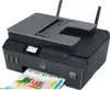 A dark gray HP Smart Tank Plus 655 Wireless AiO printer is shown from a slightly elevated front-left angle, with a printed document emerging from the output tray. Podgląd zdjęcia produktu