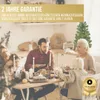 A family is gathered around a table for a Christmas dinner, with a small decorated Christmas tree in the background. Produktbild-Vorschau