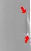 A close-up view of a refrigerator door with two red arrows pointing to a vertical line and a bright spot on the surface. Produktbild-Vorschau