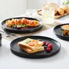 A table setting with multiple plates of food, including pasta and toast with toppings, and a glass of water. Produktbild-Vorschau