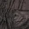 A close-up view of a dark gray, plush blanket, showing the texture and stitching of the hem. Produktbild-Vorschau