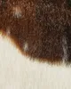 A close-up view of a faux fur rug with brown and white patches. Podgląd zdjęcia produktu