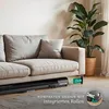 A compact treadmill is placed under a sofa in a living room, highlighting its space-saving design. Produktbild-Vorschau