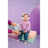 A baby wearing noise-canceling headphones sits on a multi-colored block structure, with a person's hands reaching towards them from the left. Anteprima dell’immagine prodotto