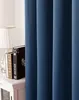 A close-up view of a dark blue curtain, partially obscuring a bedside table with books and a lamp. Produktbild-Vorschau
